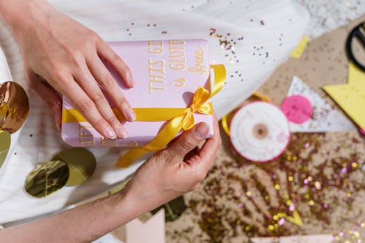 Cadeau emballé avec un ruban jaune, entouré de confettis et de décorations festives, sur un fond lumineux.